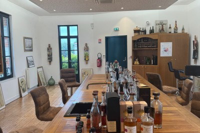 Intérieur d'un bar cosy avec un comptoir en bois, des tabourets hauts et des tables alignées dans un espace chaleureux.