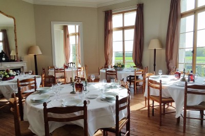 Intérieur d'un bar cosy avec un comptoir en bois, des tabourets hauts et des tables alignées dans un espace chaleureux.