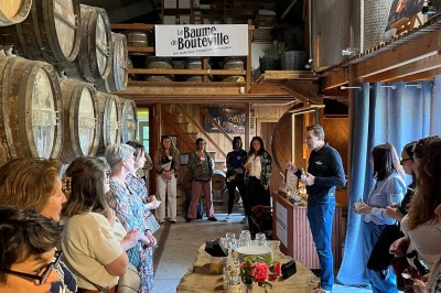 Intérieur d'un bar cosy avec un comptoir en bois, des tabourets hauts et des tables alignées dans un espace chaleureux.