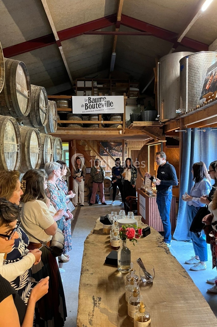 Groupe de personnes assistant à une présentation dans une salle avec des tonneaux en bois et des cuves métalliques.