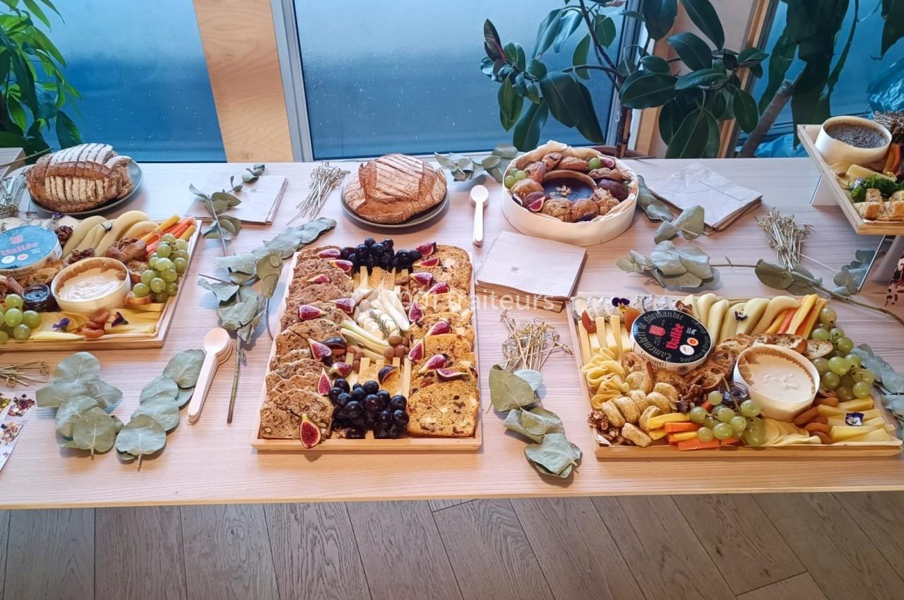 Plateau de buffet composé de fruits, légumes, pains et fromages, disposé sur une table en bois avec des décorations…