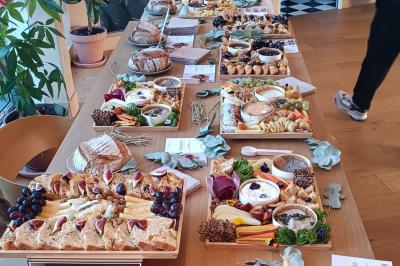 Plateau coloré de crudités, fromages, dips, fruits secs et fleurs comestibles disposés de manière artistique.