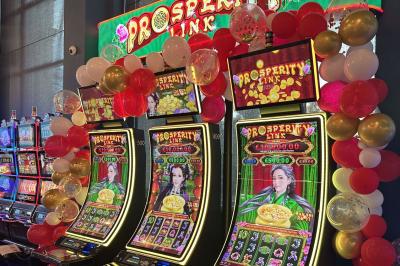 Deux machines à sous lumineuses avec écrans colorés, une personne assise devant l'une d'elles dans un casino.