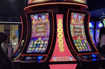 Deux machines à sous lumineuses avec écrans colorés, une personne assise devant l'une d'elles dans un casino.