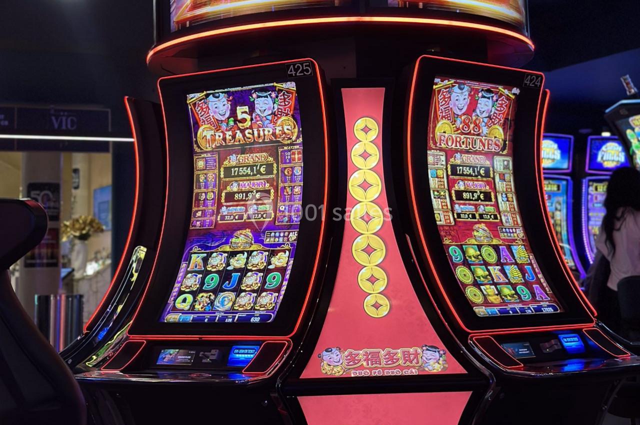 Machines à sous lumineuses avec écrans colorés affichant des jeux et des gains potentiels dans un casino.