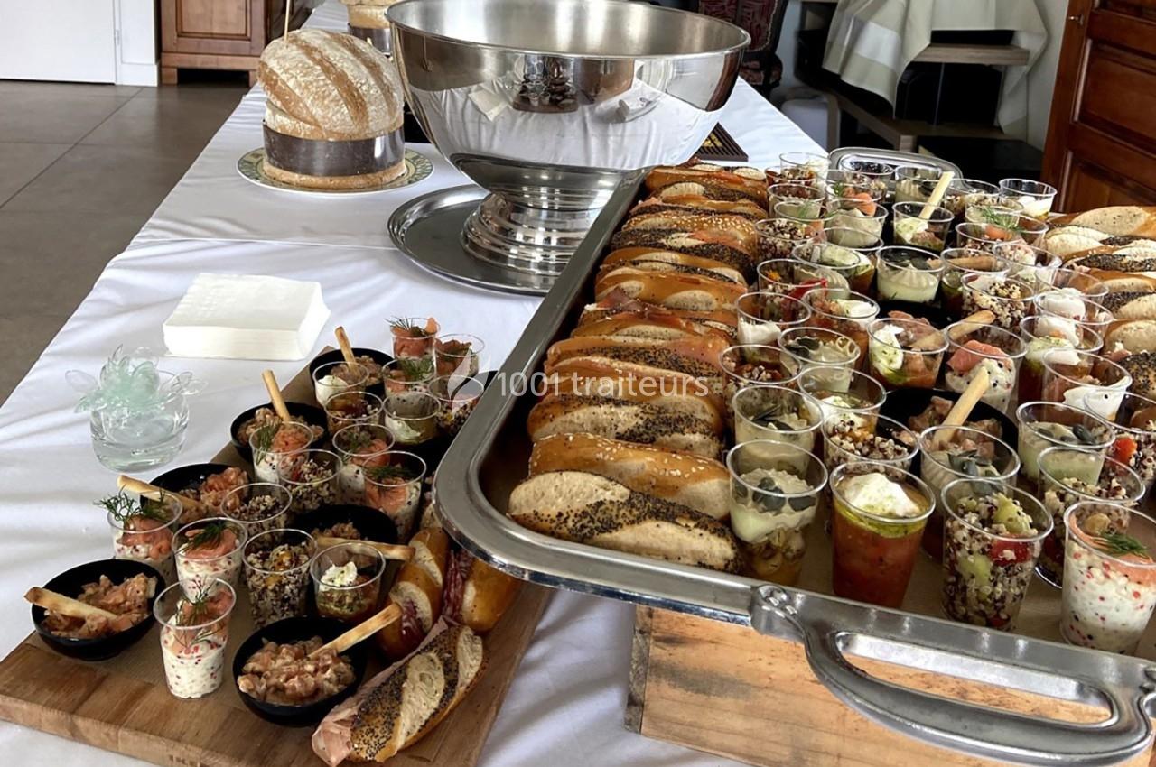 Buffet avec verrines variées, pains garnis et plats disposés sur une table blanche dans un cadre intérieur.