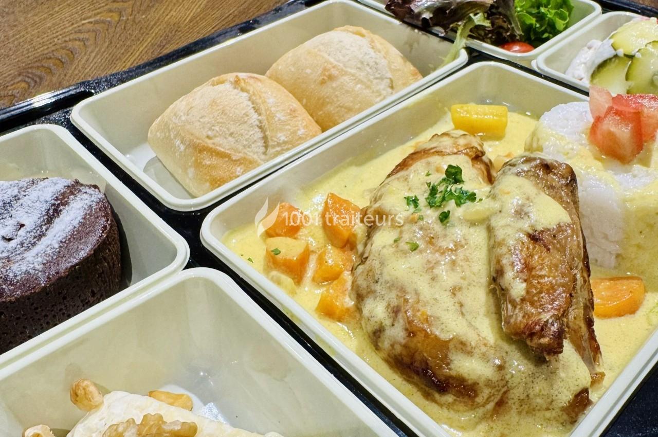 Plateau-repas avec poulet en sauce, légumes, riz, pain, dessert au chocolat et salade en accompagnement.