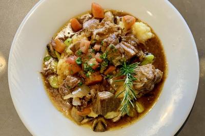 Assortiment de grillades, samoussas, légumes et sauce, garni d'oignons et tomates cerises.