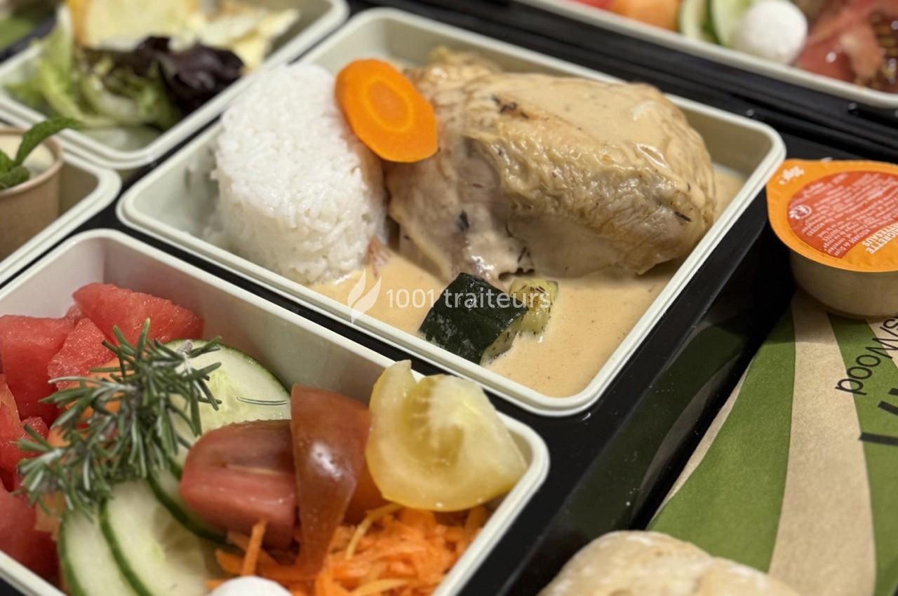 Plateau-repas avec poulet en sauce, riz, légumes variés, salade et fruits frais, présenté dans des compartiments.