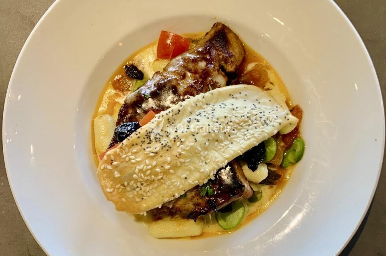 Plat servi dans une assiette blanche, composé de viande gratinée, légumes, sauce et une pâte garnie de graines.