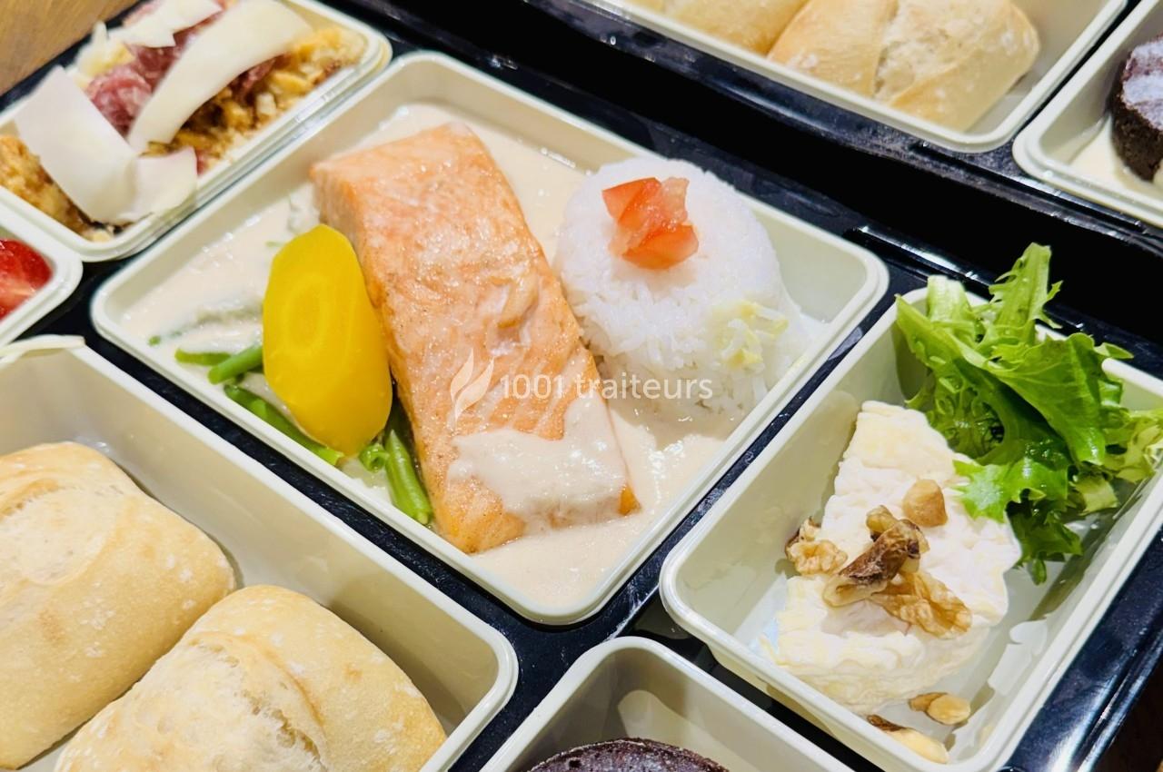 Plateau-repas avec saumon, riz, légumes, salade verte, fromage aux noix et pain, présenté dans des compartiments.