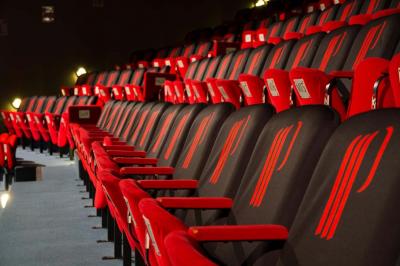 Deux machines à sous lumineuses avec écrans colorés, une personne assise devant l'une d'elles dans un casino.