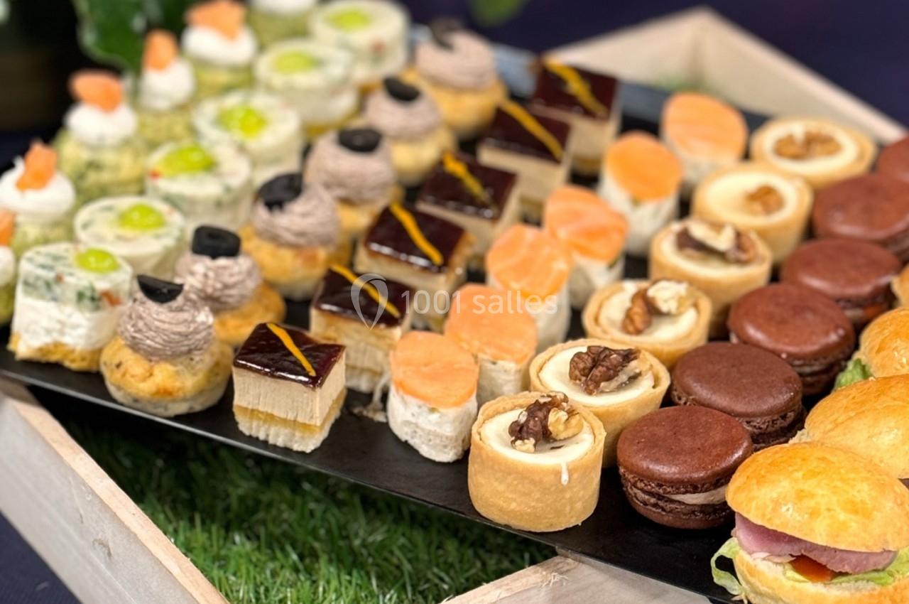 Plateau de bouchées salées et sucrées variées, comprenant macarons, tartelettes, toasts et petits sandwichs.