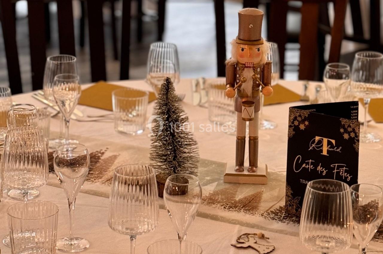 Table décorée pour les fêtes avec un casse-noisette, un petit sapin, des verres et un menu.