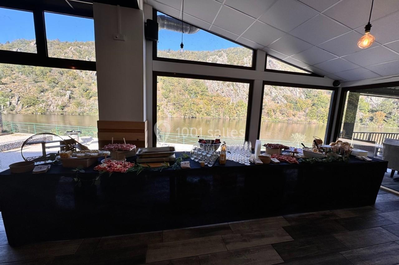 Buffet dressé dans une salle lumineuse avec vue sur un paysage naturel de rivière et collines boisées.