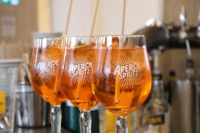 Trois verres d'Aperol Spritz garnis de glaçons et d'oranges, alignés sur un comptoir de bar.