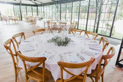 Bougies allumées sur une table décorée avec des verres, assiettes empilées et serviettes pliées.