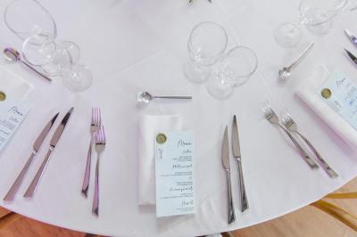 Bougies allumées sur une table décorée avec des verres, assiettes empilées et serviettes pliées.