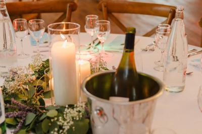 Bougies allumées sur une table décorée avec des verres, assiettes empilées et serviettes pliées.