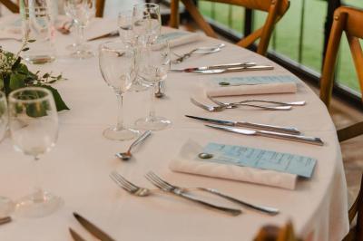 Bougies allumées sur une table décorée avec des verres, assiettes empilées et serviettes pliées.
