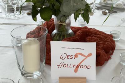 Bougies allumées sur une table décorée avec des verres, assiettes empilées et serviettes pliées.