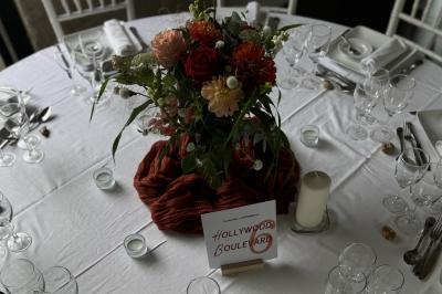 Bougies allumées sur une table décorée avec des verres, assiettes empilées et serviettes pliées.