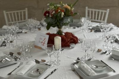 Bougies allumées sur une table décorée avec des verres, assiettes empilées et serviettes pliées.