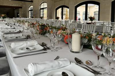 Bougies allumées sur une table décorée avec des verres, assiettes empilées et serviettes pliées.