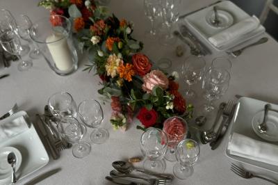 Bougies allumées sur une table décorée avec des verres, assiettes empilées et serviettes pliées.