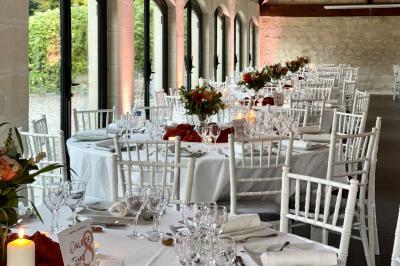 Bougies allumées sur une table décorée avec des verres, assiettes empilées et serviettes pliées.