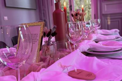 Bougies allumées sur une table décorée avec des verres, assiettes empilées et serviettes pliées.