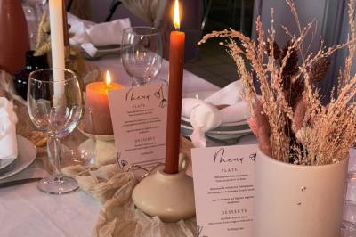 Bougies allumées sur une table décorée avec des verres, assiettes empilées et serviettes pliées.