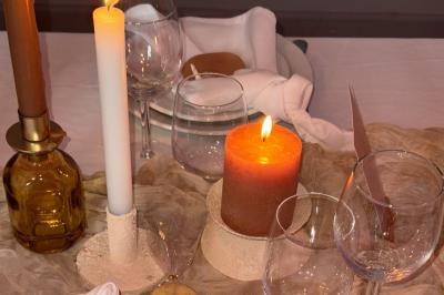 Bougies allumées sur une table décorée avec des verres, assiettes empilées et serviettes pliées.