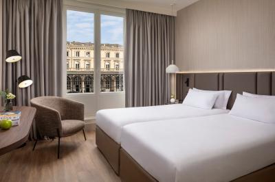 Salle de bain moderne avec lavabo suspendu, douche vitrée, toilettes et murs ornés de motifs en relief.