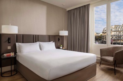 Salle de bain moderne avec lavabo suspendu, douche vitrée, toilettes et murs ornés de motifs en relief.