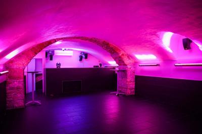 Portant en bois dans une armoire ouverte, éclairée par une lumière rose, avec plusieurs cintres suspendus.