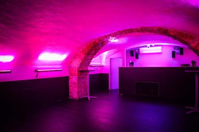 Portant en bois dans une armoire ouverte, éclairée par une lumière rose, avec plusieurs cintres suspendus.