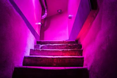 Portant en bois dans une armoire ouverte, éclairée par une lumière rose, avec plusieurs cintres suspendus.