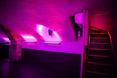 Portant en bois dans une armoire ouverte, éclairée par une lumière rose, avec plusieurs cintres suspendus.