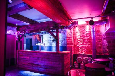 Portant en bois dans une armoire ouverte, éclairée par une lumière rose, avec plusieurs cintres suspendus.