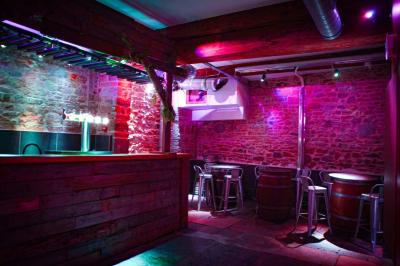 Portant en bois dans une armoire ouverte, éclairée par une lumière rose, avec plusieurs cintres suspendus.