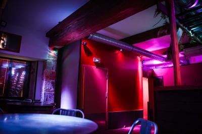 Portant en bois dans une armoire ouverte, éclairée par une lumière rose, avec plusieurs cintres suspendus.