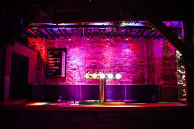 Portant en bois dans une armoire ouverte, éclairée par une lumière rose, avec plusieurs cintres suspendus.