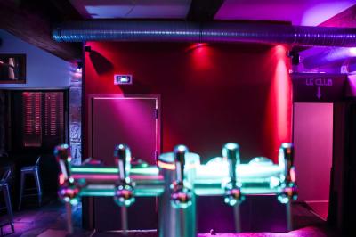 Portant en bois dans une armoire ouverte, éclairée par une lumière rose, avec plusieurs cintres suspendus.