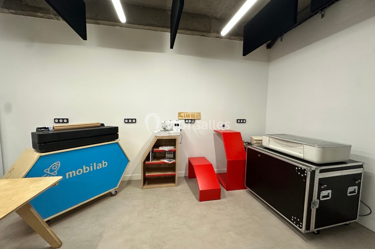 Espace de fabrication équipé de machines et rangements, avec un décor minimaliste et des murs blancs.