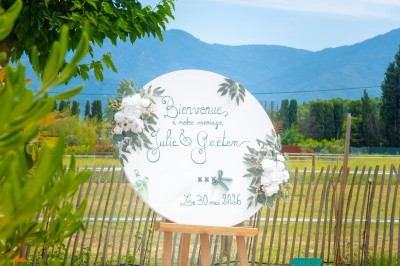 Un groupe de personnes, dont un couple en tenue de mariage, pose en extérieur devant un paysage montagneux.