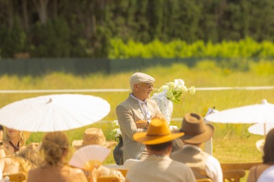 Un groupe de personnes, dont un couple en tenue de mariage, pose en extérieur devant un paysage montagneux.