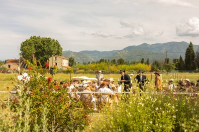 Un groupe de personnes, dont un couple en tenue de mariage, pose en extérieur devant un paysage montagneux.