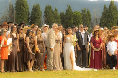 Un groupe de personnes, dont un couple en tenue de mariage, pose en extérieur devant un paysage montagneux.