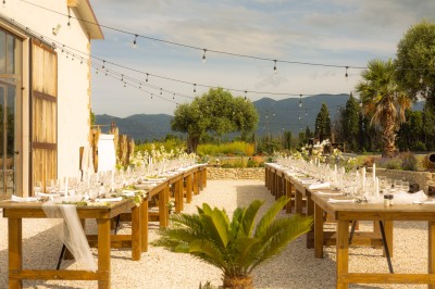 Un groupe de personnes, dont un couple en tenue de mariage, pose en extérieur devant un paysage montagneux.